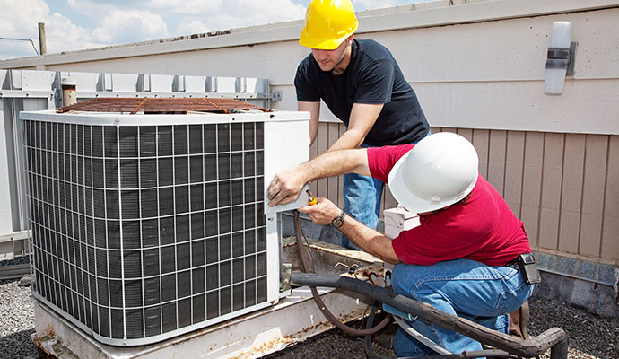 HVAC technicians repairing an outdoor air conditioning condenser