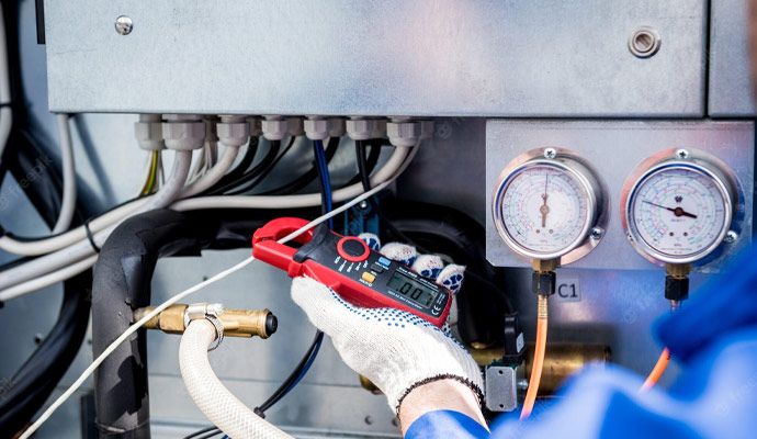Technician using a clamp meter to check the power lines of a heating system