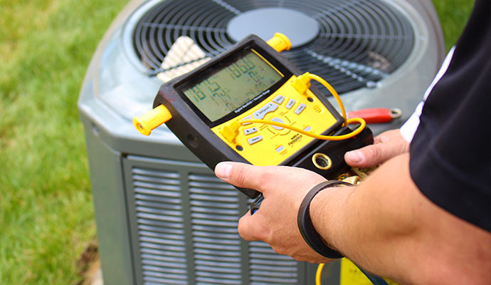 Technician holding digital gauge tool in front of outdoor air conditioning unit