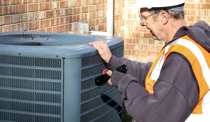 Technician wearing safety vest inspecting outdoor air conditioning condenser unit
