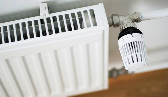 A close-up of a white panel radiator with a thermostatic